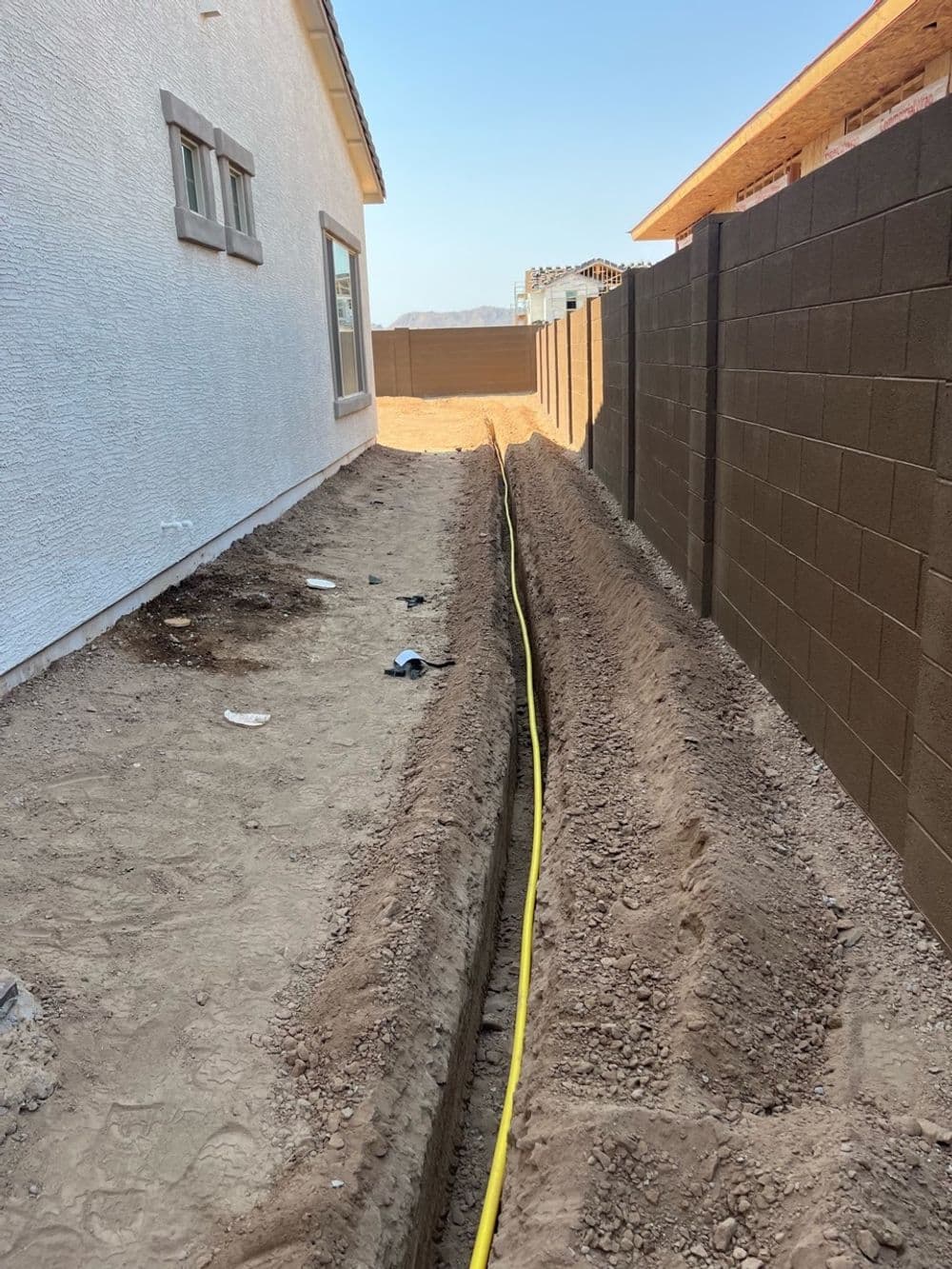 Excavated trench alongside a home for utility installation in a residential area.