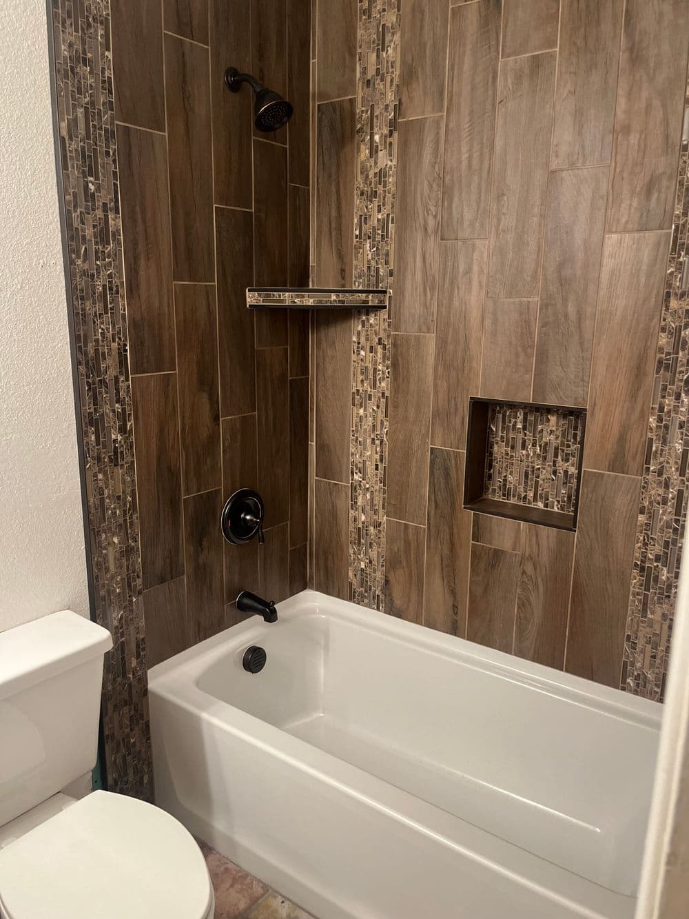 Modern bathroom with a stylish tub, brown tiled walls, and sleek black fixtures.